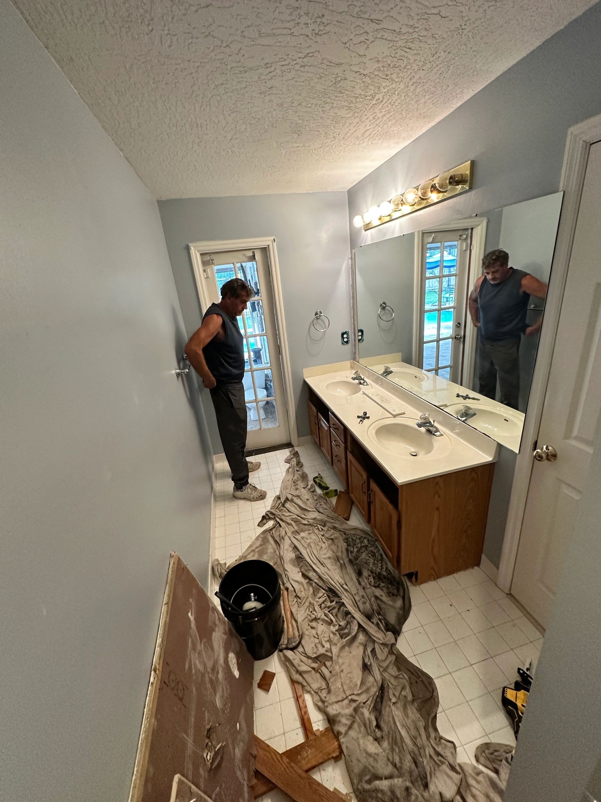 Bathroom remodel Oct 2025 — worker assessing the space before demolition