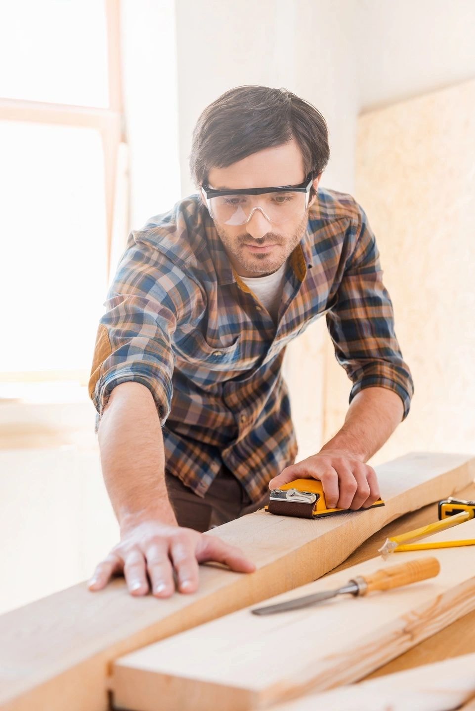 Carpenter measuring wood with safety glasses